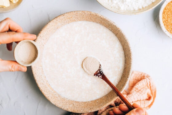 Stirring in yeast to warmed almond milk in a bowl.