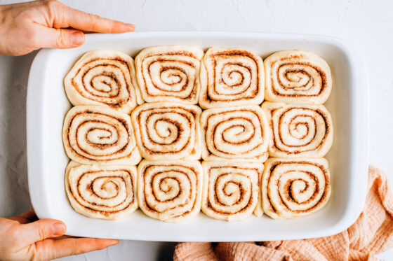 Twelve cinnamon rolls added to a baking dish.