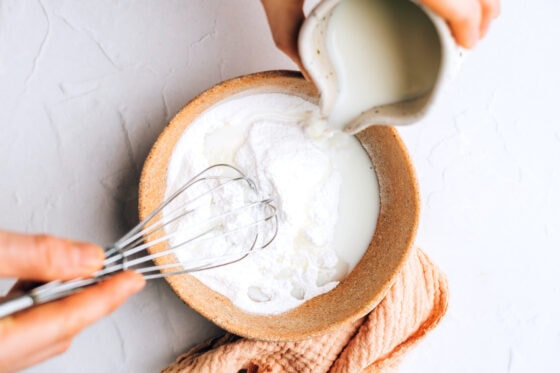 Mixing together almond milk and confectioner's sugar in a bowl to make a glaze.