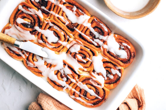 Topping vegan cinnamon rolls with glaze.