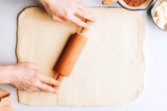 Rolling cinnamon roll dough into a rectangle.
