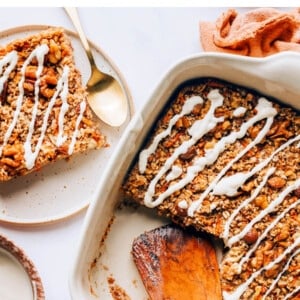 A baking dish containing carrot cake baked oatmeal. A plate with a slice is next to the dish.