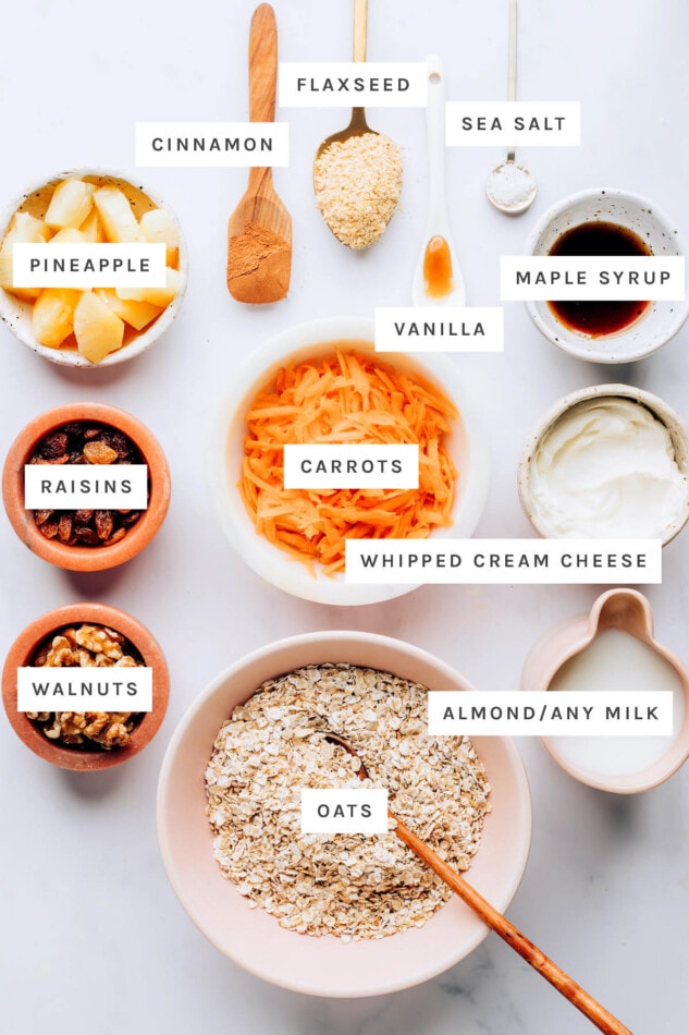 Ingredients measured out to make carrot cake baked oatmeal: cinnamon, flaxseed, vanilla, sea salt, maple syrup, pineapple, carrots, raisins, whipped cream cheese, walnuts, oats and almond milk.