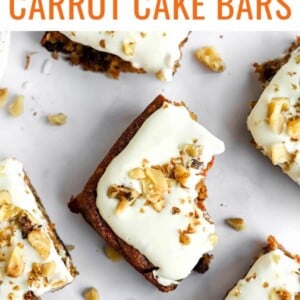 Several squares of carrot cake bars spread around. The center bar has a bite removed.