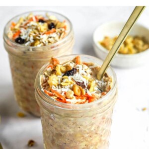 Two jars of carrot cake overnight oats. A spoon is sticking out of the front jar.