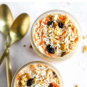 Bird's eye view of two jars of carrot cake overnight oats. Two spoons are beside the jars.