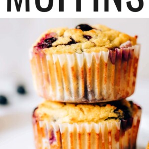 Two coconut flour muffins wrapped in paper liners stacked on top of each other.