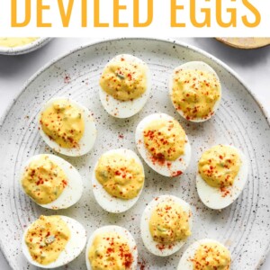 A serving plate with healthy deviled eggs topped with paprika.