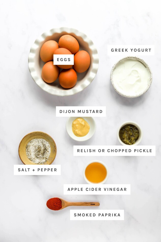 Ingredients measured out to make healthy deviled eggs: eggs, relish, salt, pepper, apple cider vinegar and smoked paprika.Greek yogurt, dijon mustard,
