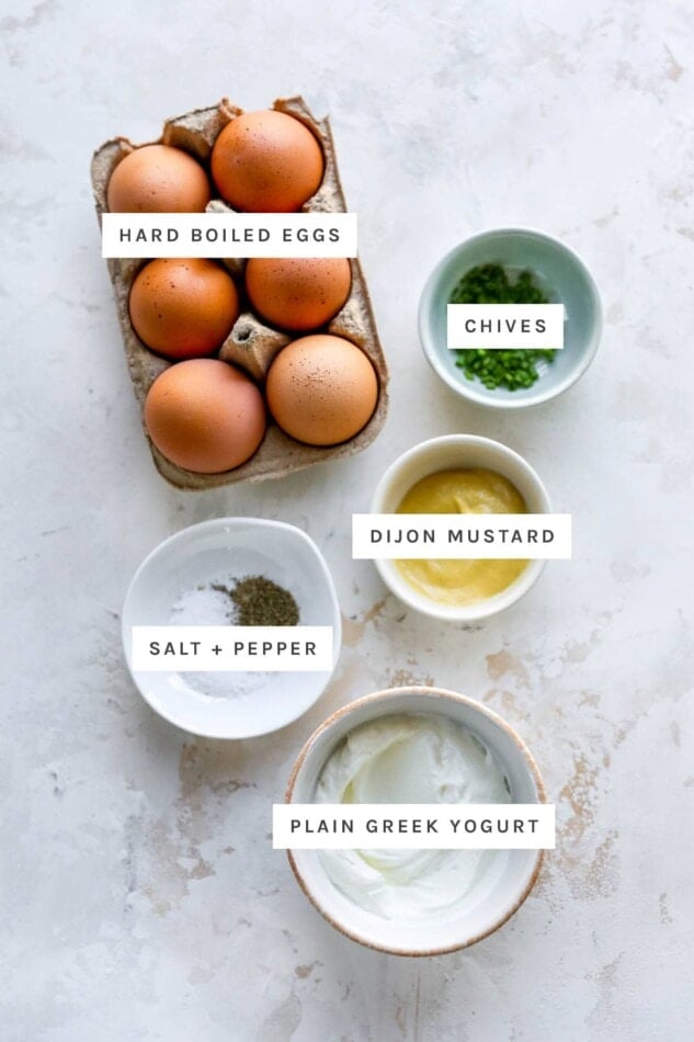 Ingredients measured out to make healthy egg salad: hard-boiled eggs, chives, dijon, salt, pepper and plain Greek yogurt.