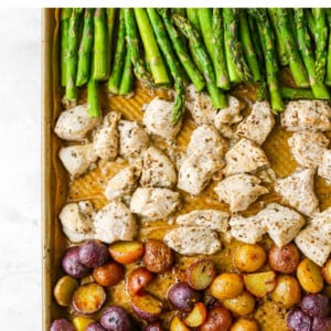 A sheet pan with rows of asparagus, chicken and potatoes.