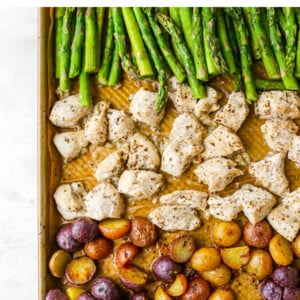 A sheet pan with rows of asparagus, chicken and potatoes.