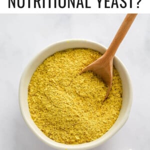 Bowl of nutritional yeast with a wooden spoon in the bowl.