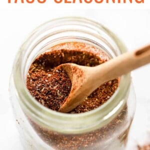 Taco seasoning in a small spice jar. A wooden spoon is resting in the jar.