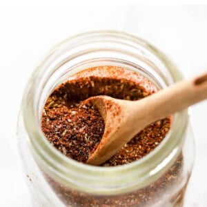 Taco seasoning in a small spice jar. A wooden spoon is resting in the jar.