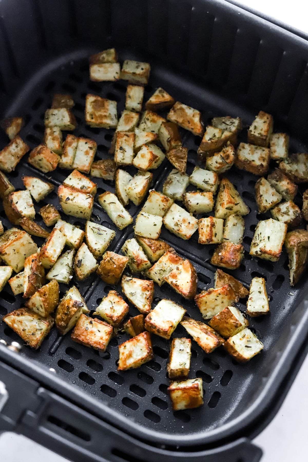 Air fried breakfast potatoes in an air fryer basket.