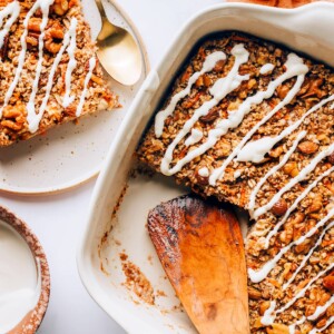 A baking dish containing carrot cake baked oatmeal. A plate with a slice is next to the dish.