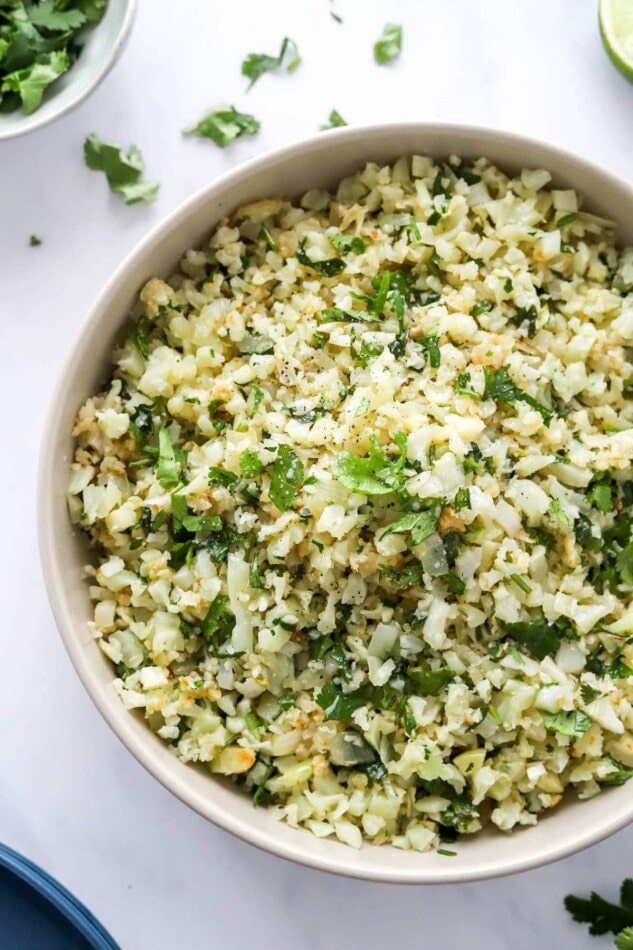 A closeup of a serving bowl containing cilantro lime cauliflower rice.