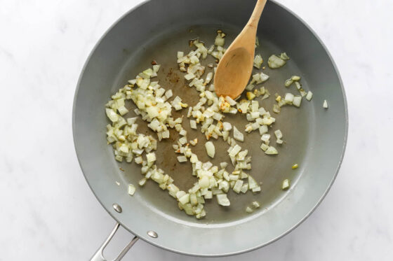 Sautéing onion and garlic in a pan.