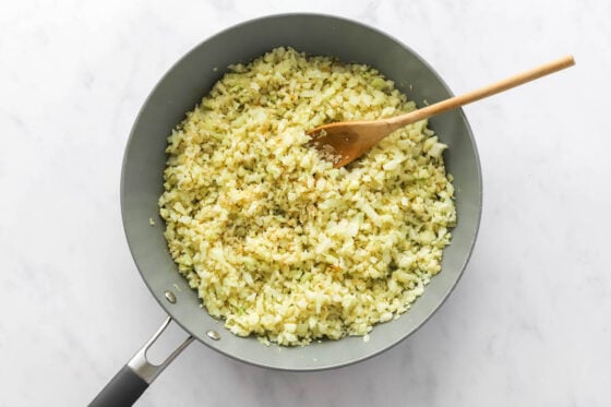 Cooking cauliflower rice in the onion and garlic.