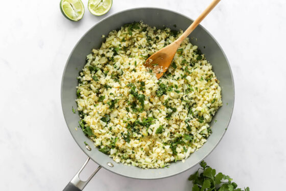 Cilantro and lime juice added to cauliflower rice in a sauté pan.