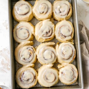 12 cinnamon rolls that have been iced, placed in a baking pan.
