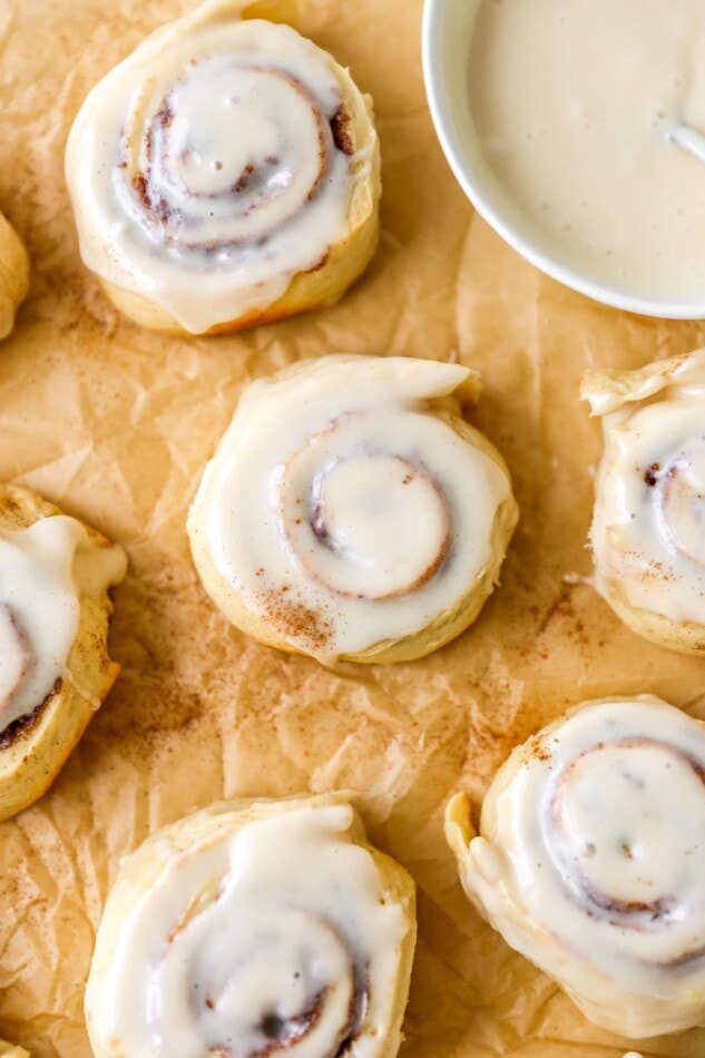 An overhead photo looking at an iced cinnamon roll. Other cinnamon rolls are around the center roll.