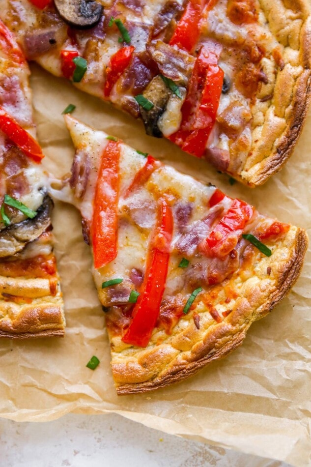 Closeup of a slice of cloud bread pizza on a sheet of brown parchment paper.