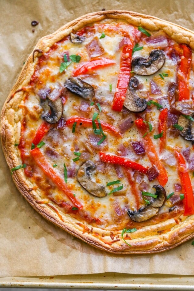 Closeup of a cloud bread pizza on a sheet of brown parchment paper.