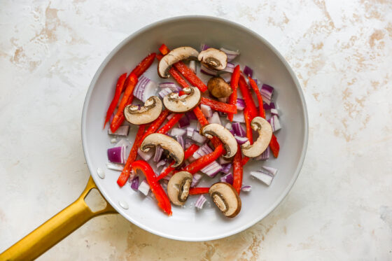 Sautéing onion, bell pepper and mushrooms in a sauté pan.