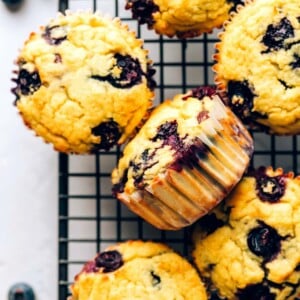 An overhead view of coconut flour muffins arranged on a wire cooling rack. One muffin is turned on its side.