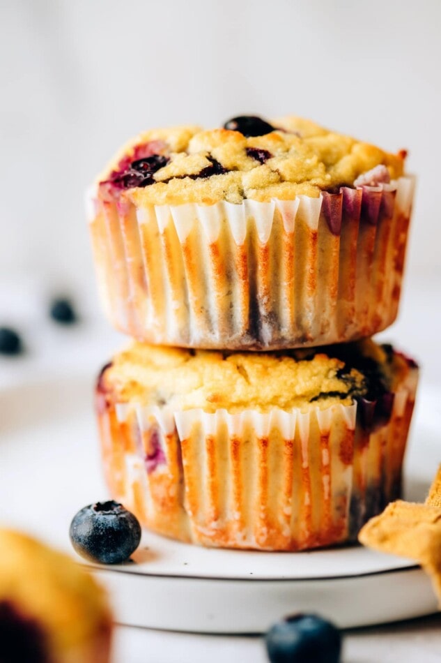 Two coconut flour muffins wrapped in paper liners stacked on top of each other.