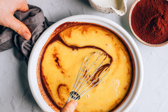 Whisking in eggs to the chocolate mixture in a saucepan.