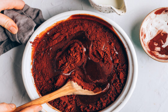 Mixing in cocoa powder to the chocolate mixture in a saucepan.