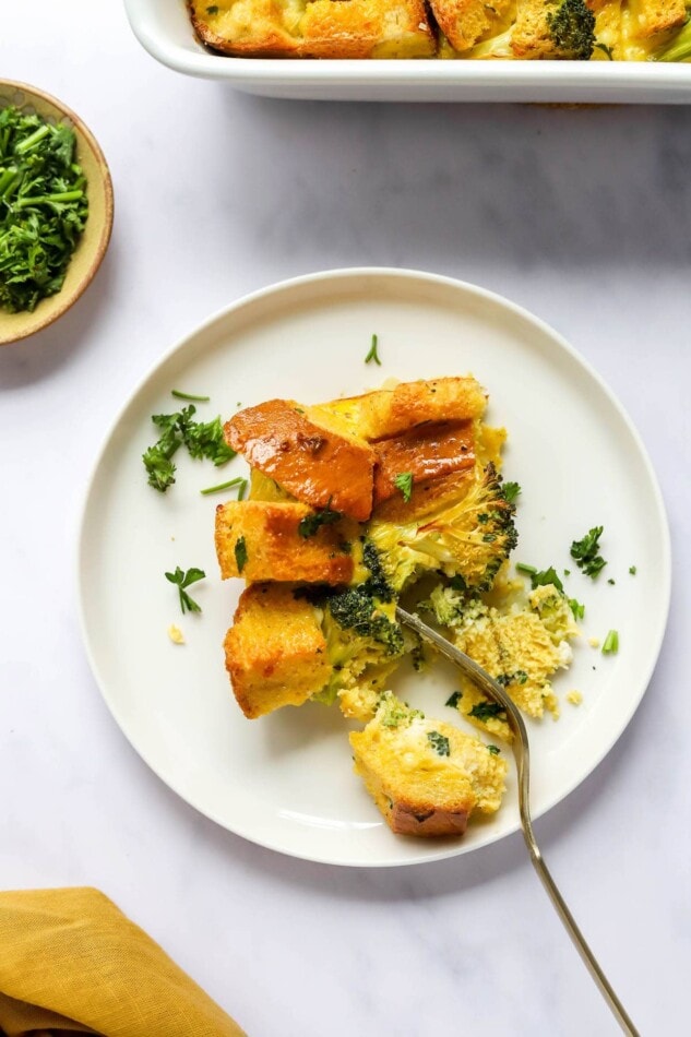 A serving of breakfast casserole on a plate with a fork.