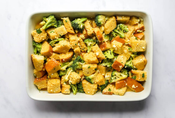 Egg mixture poured of cubes of gluten free bread in a baking dish.