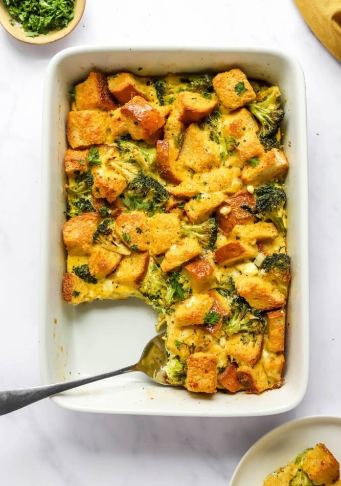 A baking dish containing healthy breakfast casserole. A portion is missing from the baking dish and a spoon rests in its place.