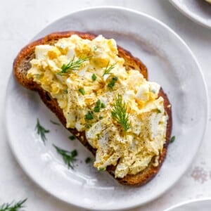 A plate with a slice of bread topped with healthy egg salad.