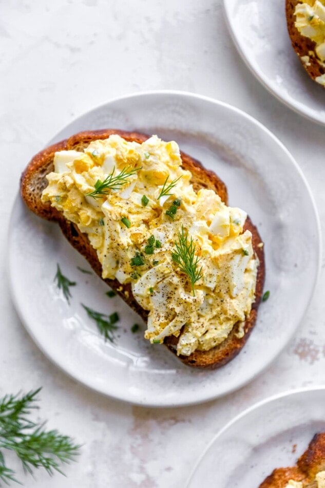 A plate with a slice of bread topped with healthy egg salad.