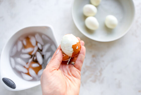 Peeling a hardboiled egg to remove the shell.