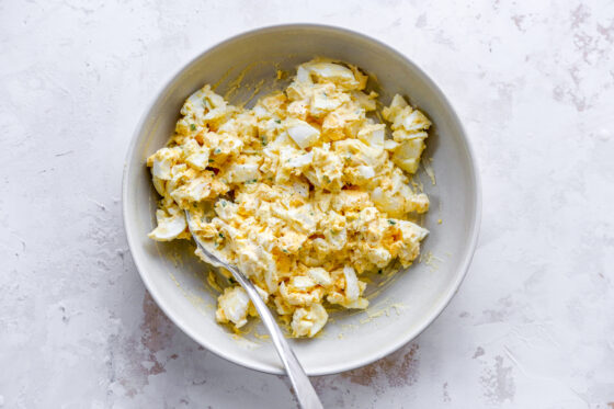 Healthy egg salad in a bowl. A spoon rests in the bowl.
