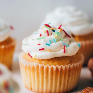 A health vanilla cupcake topped with icing and sprinkles.