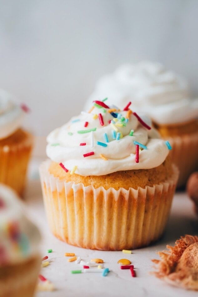 A health vanilla cupcake topped with icing and sprinkles.