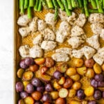 A sheet pan with rows of asparagus, chicken and potatoes.