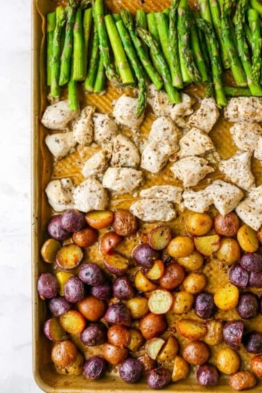 A sheet pan with rows of asparagus, chicken and potatoes.