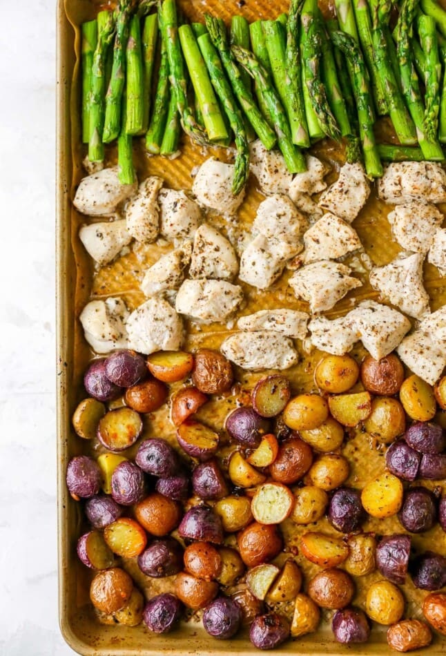 A sheet pan with rows of asparagus, chicken and potatoes.