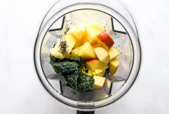 Apple, pineapple, coconut water, kale, lemon juice, fresh ginger and chia seeds in a blender.