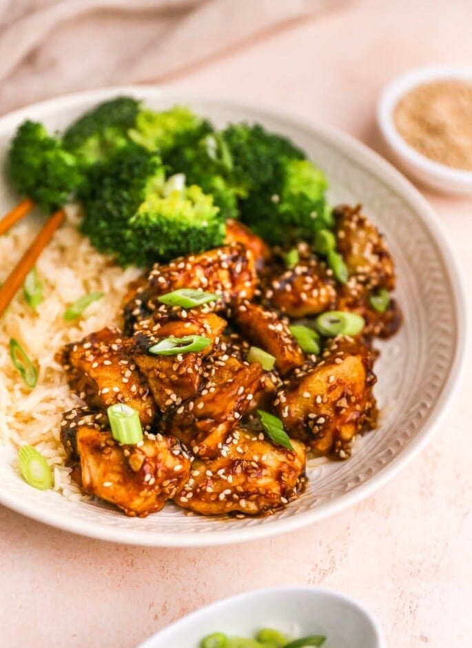 Sesame chicken served on a plate with rice and broccoli.