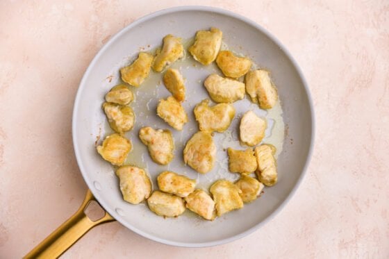 Chicken cooking on a pan in olive oil.