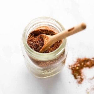 Taco seasoning in a small spice jar. A wooden spoon is resting in the jar.